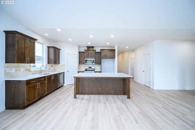 kitchen with a center island, stainless steel appliances, tasteful backsplash, light hardwood / wood-style floors, and sink