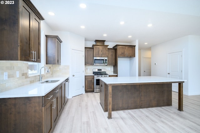 kitchen featuring appliances with stainless steel finishes, sink, a kitchen breakfast bar, light hardwood / wood-style flooring, and a center island