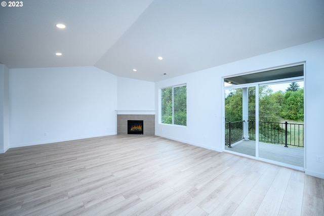 unfurnished living room with light wood-type flooring, vaulted ceiling, and a fireplace