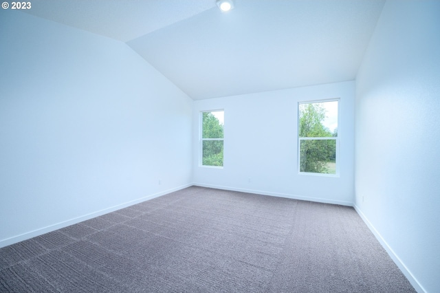 carpeted empty room with lofted ceiling