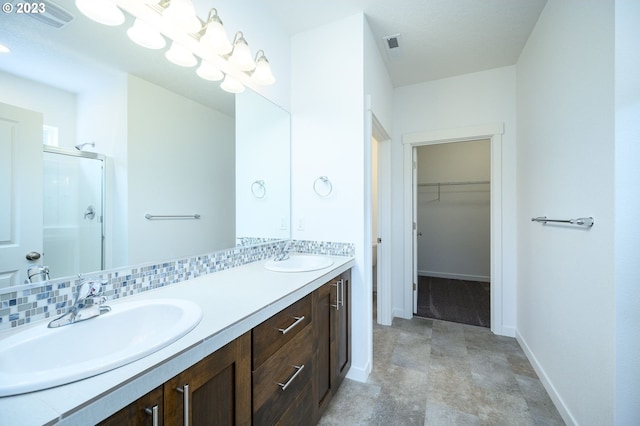 bathroom featuring a shower with shower door, backsplash, and vanity