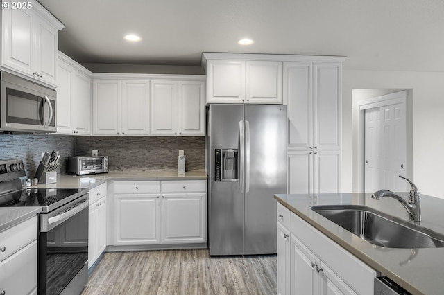 kitchen with sink, stainless steel appliances, light hardwood / wood-style flooring, backsplash, and white cabinets