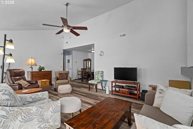 living area with ceiling fan, high vaulted ceiling, and wood finished floors