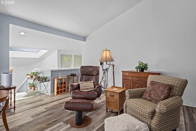 living area featuring a skylight, vaulted ceiling, wood finished floors, and recessed lighting