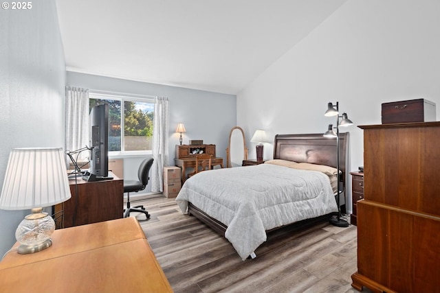 bedroom featuring wood finished floors, an office area, and vaulted ceiling