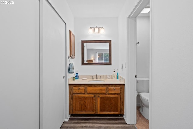 bathroom with toilet, vanity, and wood finished floors
