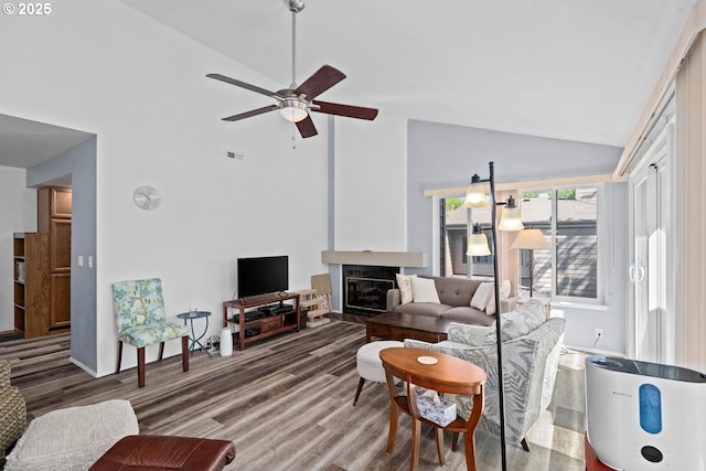 living area featuring high vaulted ceiling, ceiling fan, wood finished floors, and a fireplace