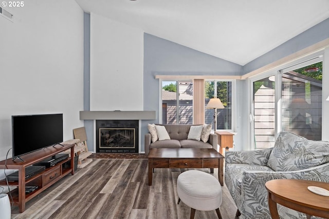 living room featuring lofted ceiling, wood finished floors, plenty of natural light, and a glass covered fireplace