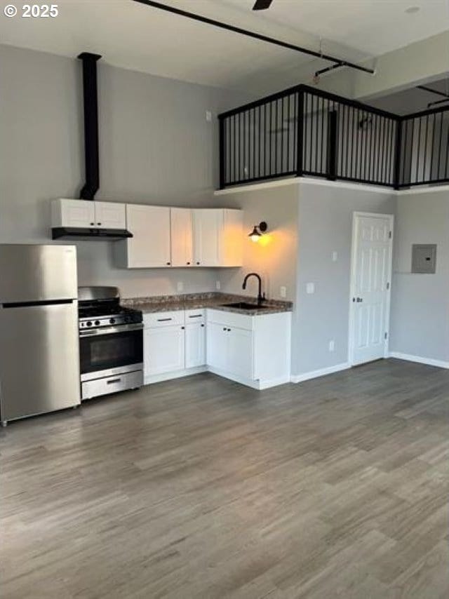 1127 6th Ave, Albany, OR 97321 - kitchen featuring appliances with stainless steel finishes, a towering ceiling, dark countertops, white cabinetry, and dark wood finished floors