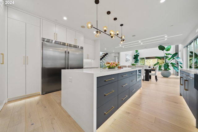 750 NE Province Ct, Camas, WA 98607 - kitchen with stainless steel built in refrigerator, white cabinetry, a kitchen island, light wood-type flooring, and light countertops