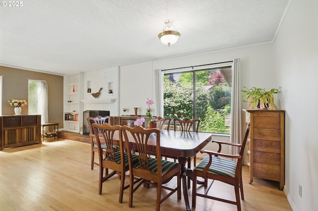 19985 SW Carlin Blvd, Beaverton, OR 97078 - dining area featuring light wood-style floors, a textured ceiling, built in features, crown molding, and a brick fireplace