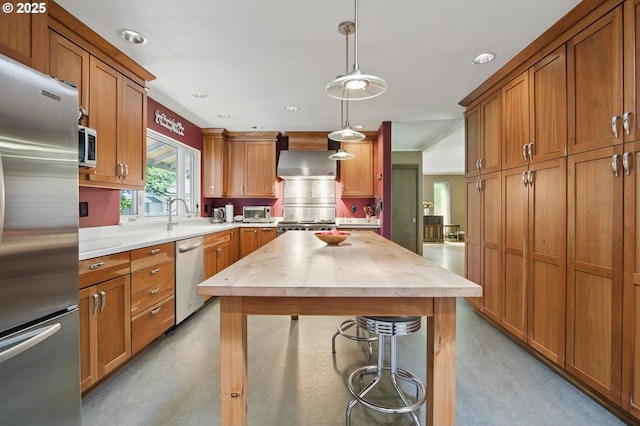 19985 SW Carlin Blvd, Beaverton, OR 97078 - kitchen featuring appliances with stainless steel finishes, butcher block counters, wall chimney range hood, brown cabinetry, and hanging light fixtures