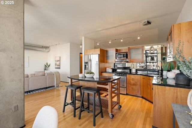 333 NW 9th Ave Unit 1323, Portland, OR 97209 - kitchen with stainless steel appliances, rail lighting, a sink, light wood finished floors, and dark countertops