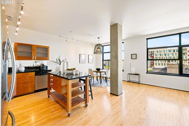 333 NW 9th Ave Unit 1323, Portland, OR 97209 - kitchen with stainless steel appliances, light wood finished floors, rail lighting, glass insert cabinets, and dark countertops