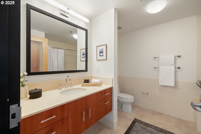 bathroom with tile patterned floors, toilet, tile walls, vanity, and curtained shower