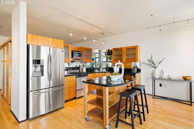 333 NW 9th Ave Unit 1323, Portland, OR 97209 - kitchen featuring stainless steel appliances, light wood-style floors, rail lighting, glass insert cabinets, and dark countertops