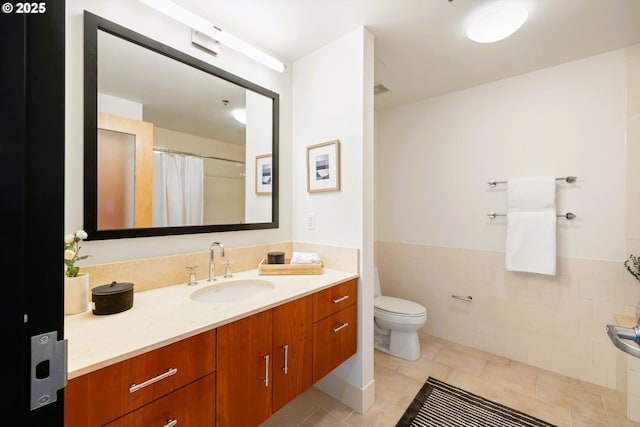 333 NW 9th Ave Unit 1323, Portland, OR 97209 - bathroom featuring vanity, toilet, wainscoting, tile patterned flooring, and tile walls