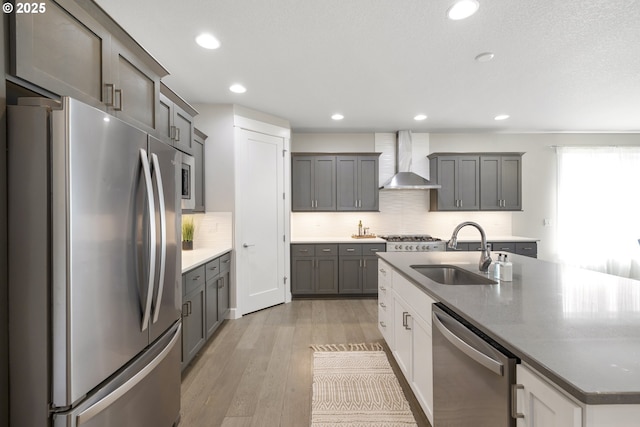 21338 SW Simon Ter, Sherwood, OR 97140 - kitchen with stainless steel appliances, wall chimney range hood, an island with sink, tasteful backsplash, and light wood-style floors