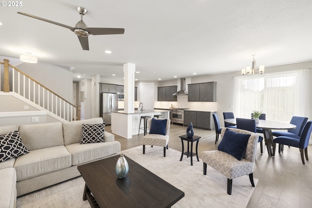21338 SW Simon Ter, Sherwood, OR 97140 - living room featuring light wood-style flooring, stairs, a chandelier, a ceiling fan, and recessed lighting