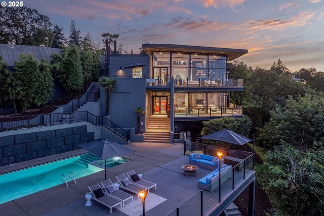 1551 SW Upper Hall St, Portland, OR 97201 - back of property at dusk with an outdoor fire pit, stairs, a balcony, and a patio