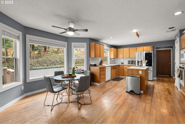 7820 SE 114th Ave, Portland, OR 97266 - kitchen with white appliances, light countertops, light wood-style flooring, tasteful backsplash, and a textured ceiling