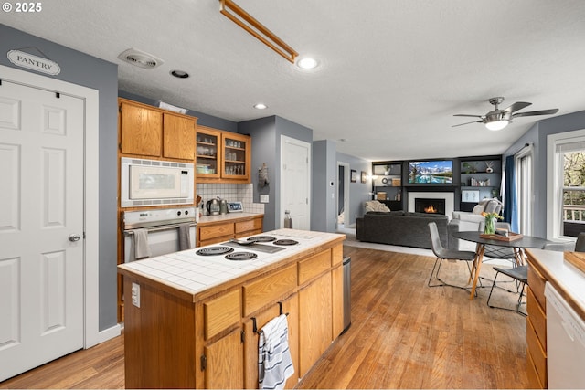 7820 SE 114th Ave, Portland, OR 97266 - kitchen featuring tile countertops, white appliances, a ceiling fan, light wood finished floors, and a lit fireplace