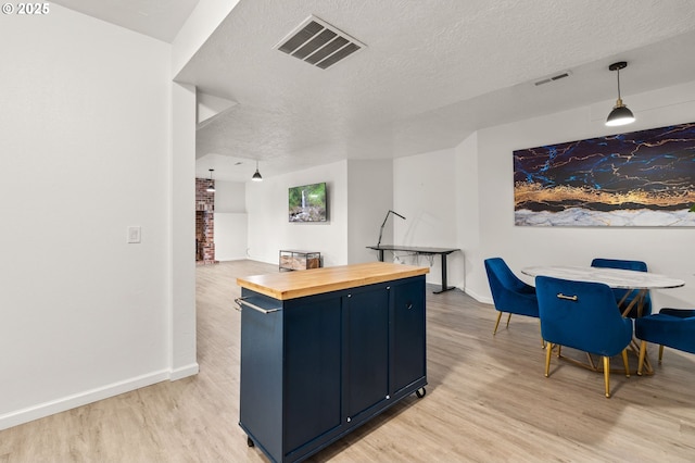 7820 SE 114th Ave, Portland, OR 97266 - kitchen featuring butcher block countertops, light wood-type flooring, blue cabinets, a textured ceiling, and baseboards