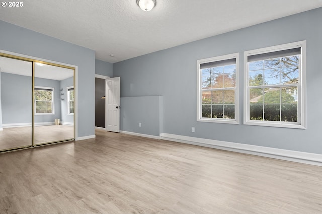 7820 SE 114th Ave, Portland, OR 97266 - unfurnished bedroom featuring wood finished floors, baseboards, a textured ceiling, and a closet
