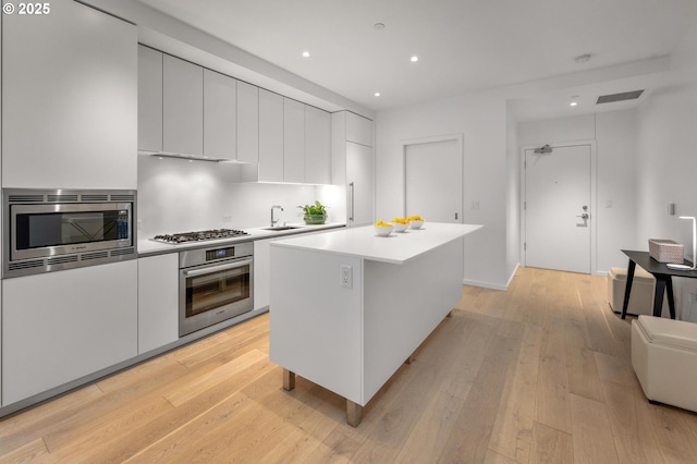 kitchen featuring light wood-style flooring, appliances with stainless steel finishes, modern cabinets, and a sink