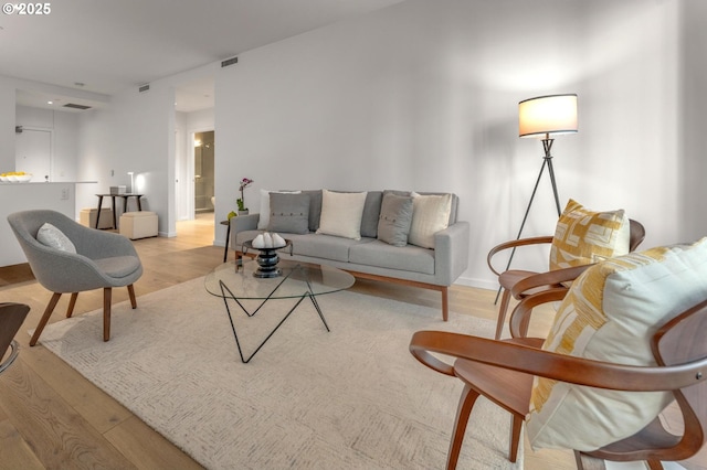 living room featuring visible vents, light wood-style flooring, and baseboards