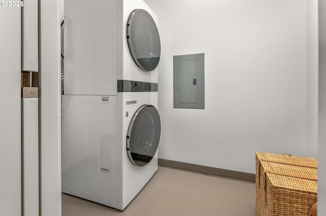 laundry room with electric panel, stacked washer / dryer, laundry area, and baseboards