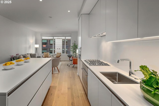 kitchen with stainless steel gas stovetop, light wood-style flooring, modern cabinets, and a sink