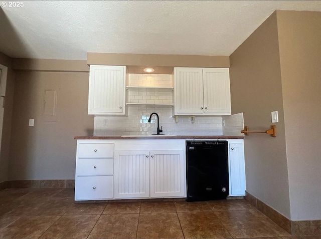 kitchen with black dishwasher, a sink, baseboards, backsplash, and white cabinetry