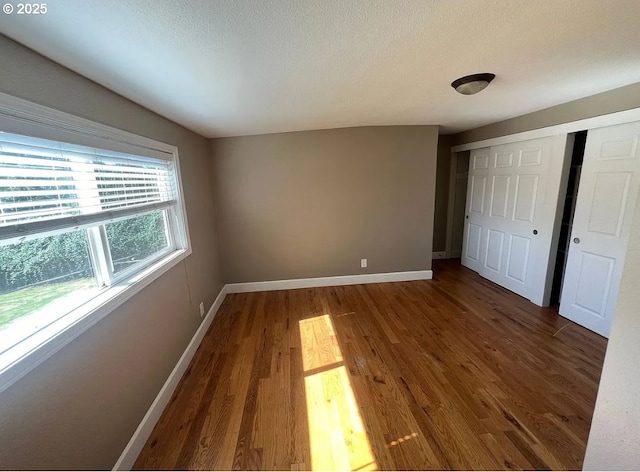 unfurnished bedroom with dark hardwood / wood-style floors, a textured ceiling, and a closet