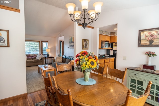 dining area with an inviting chandelier, vaulted ceiling, wood finished floors, and baseboards