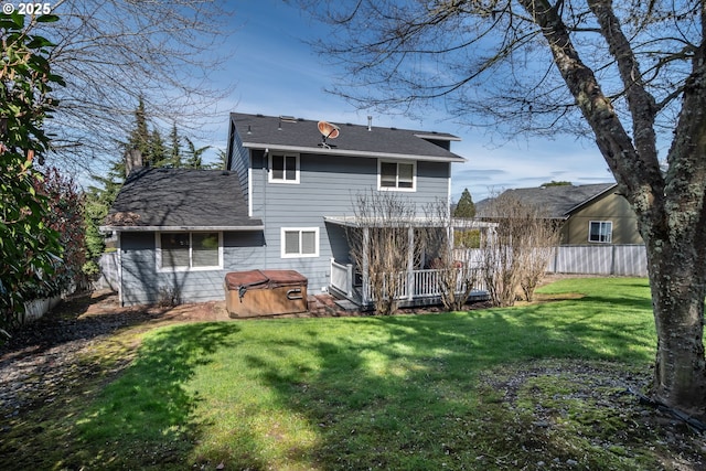 rear view of property featuring a lawn, fence, a wooden deck, a chimney, and a hot tub