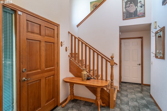 foyer entrance featuring stone finish floor, stairs, and baseboards