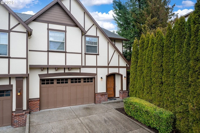 english style home featuring a garage, stucco siding, concrete driveway, and brick siding
