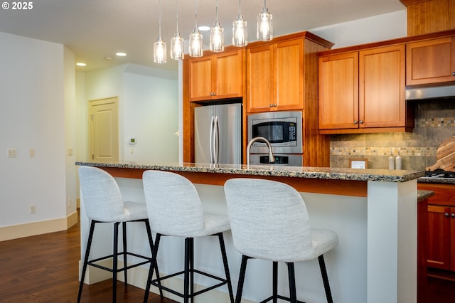 kitchen featuring decorative backsplash, a kitchen bar, appliances with stainless steel finishes, recessed lighting, and dark wood-type flooring