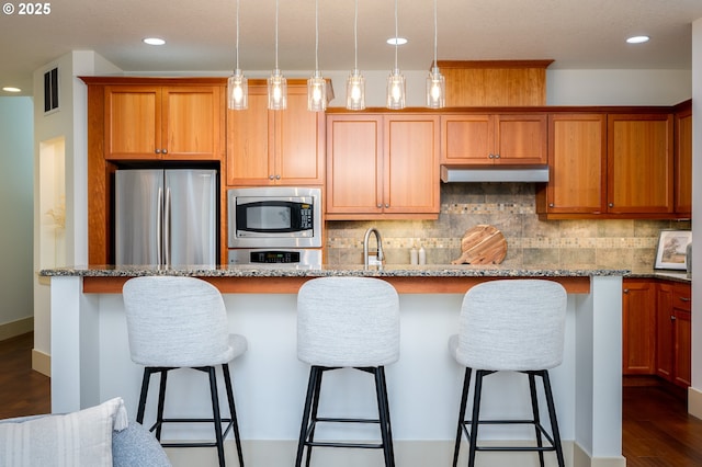kitchen featuring appliances with stainless steel finishes, recessed lighting, tasteful backsplash, under cabinet range hood, and visible vents