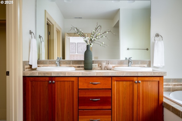 full bathroom with visible vents, a sink, double vanity, and a relaxing tiled tub