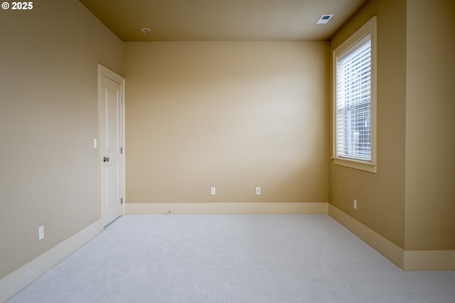 carpeted spare room featuring baseboards and visible vents