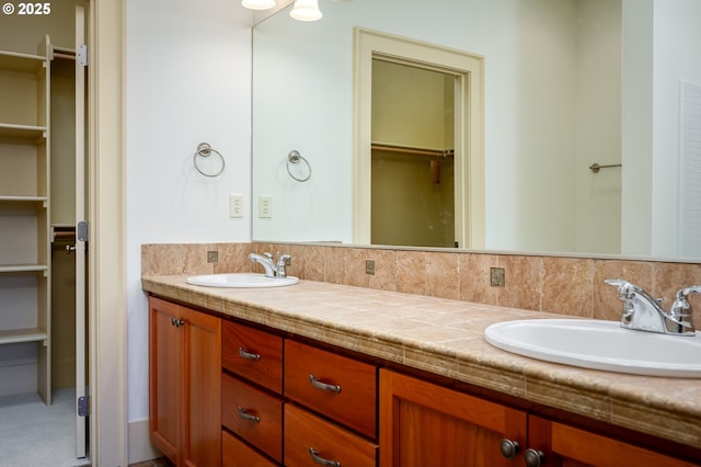bathroom featuring double vanity, a sink, and a spacious closet