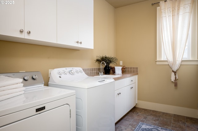 laundry room with baseboards, stone finish floor, a sink, cabinet space, and independent washer and dryer