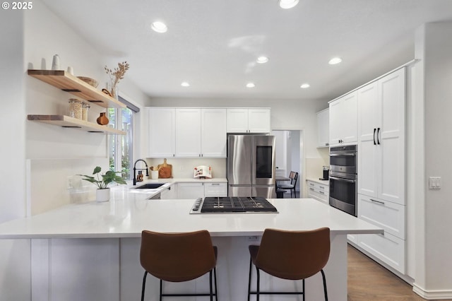 3840 NW Loy Ct, Portland, OR 97229 - kitchen with appliances with stainless steel finishes, a peninsula, a kitchen bar, white cabinetry, and recessed lighting
