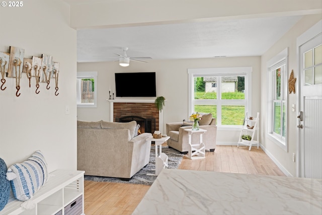 1331 NE Dallas St, Camas, WA 98607 - living room featuring wood finished floors, a warm lit fireplace, ceiling fan, and baseboards