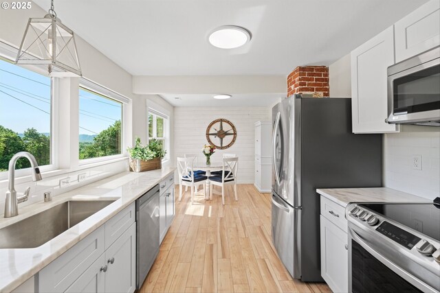 1331 NE Dallas St, Camas, WA 98607 - kitchen with stainless steel appliances, a sink, light wood-style floors, decorative backsplash, and white cabinets