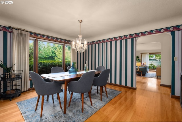 1134 NE Cesar E Chavez Blvd, Portland, OR 97232 - dining area with a chandelier, arched walkways, wood finished floors, and wallpapered walls