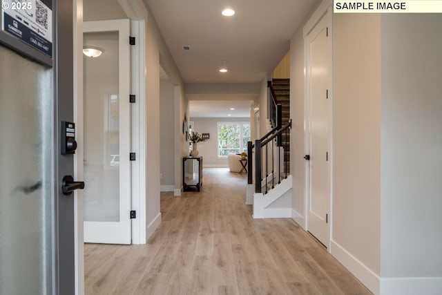 hallway featuring baseboards, stairway, light wood-type flooring, and recessed lighting