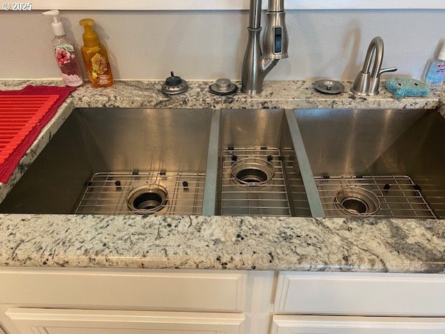 5944 SW Wilbard St, Portland, OR 97219 - kitchen view of light stone countertops, white cabinetry, and a sink